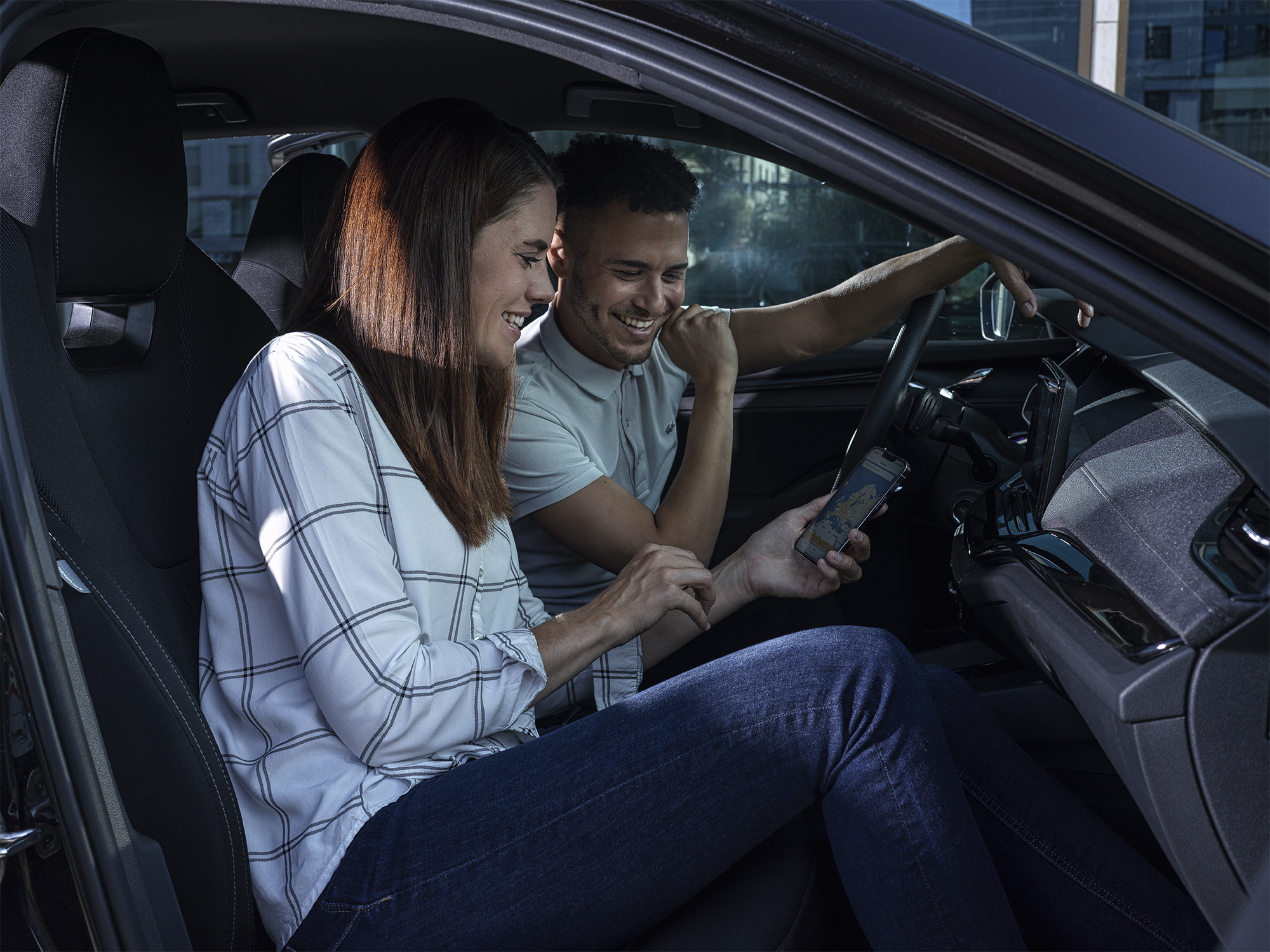 Zwei Personen sitzen bei einer Fahrgemeinschaft im Auto und sehen sich die Kosten der Fahrt an